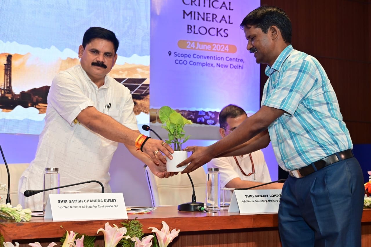 Satish Chandra Dubey on stage presenting a potted plant, in front of a backdrop reading Critical Mineral Blocks, 24 June 2024, Scope Convention Centre, CGO Complex, New Delhi