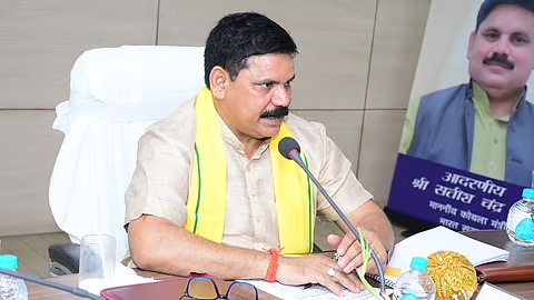 Satish Chandra Dubey chairing a review meeting at Eastern Coalfields Limited, wearing a yellow stole, speaking into a table microphone
