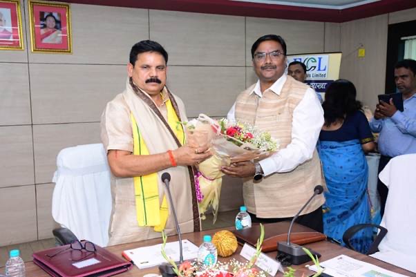 Satish Chandra Dubey being welcomed with a bouquet at an Eastern Coalfields Limited meeting room, with the ECL logo on a banner behind