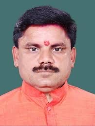 Head-and-shoulders portrait of Satish Chandra Dubey in a saffron kurta against a teal background