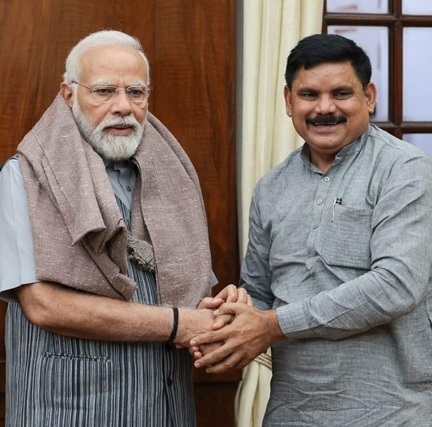 Satish Chandra Dubey, in a grey kurta, clasping hands with Prime Minister Narendra Modi