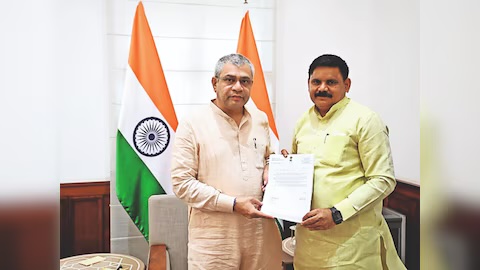 Satish Chandra Dubey handing a letter to Union Railway Minister Ashwini Vaishnaw in an office with the national flag behind them