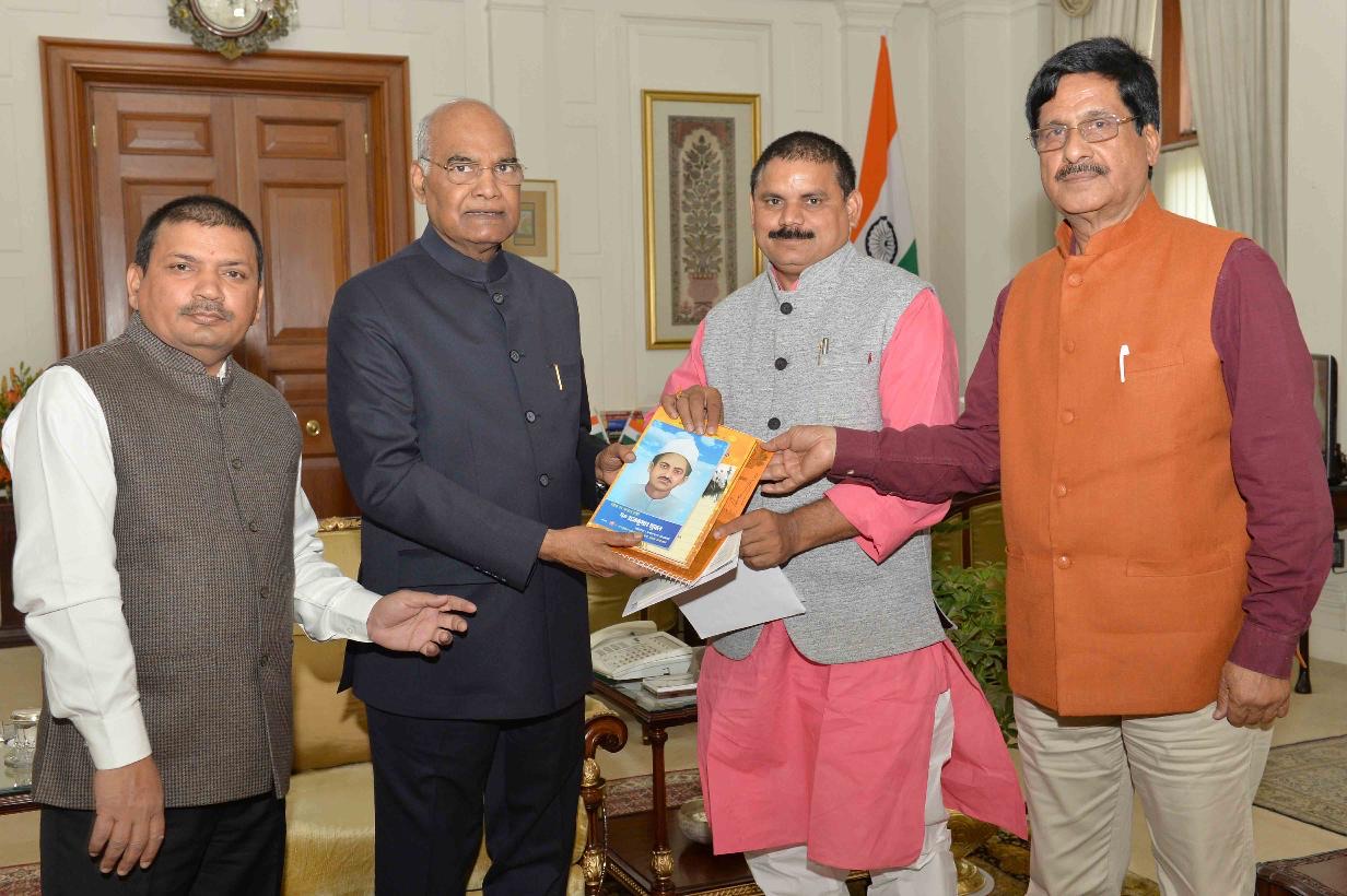 Satish Chandra Dubey, in a pink kurta and grey waistcoat, presents a book to President Ram Nath Kovind at Rashtrapati Bhavan, with two other men